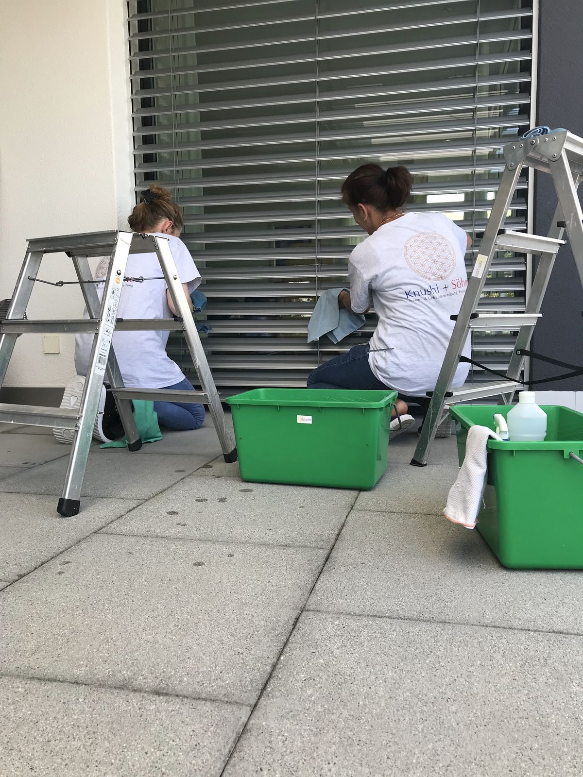 Zwei Mitarbeiterinnen reinigen eine Terrasse und die Storen