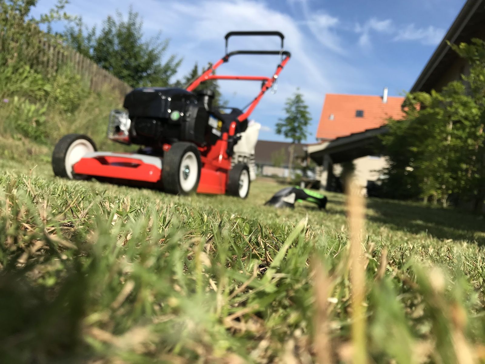 Roter Rasenmäher im Gras bei der Rasenpflege